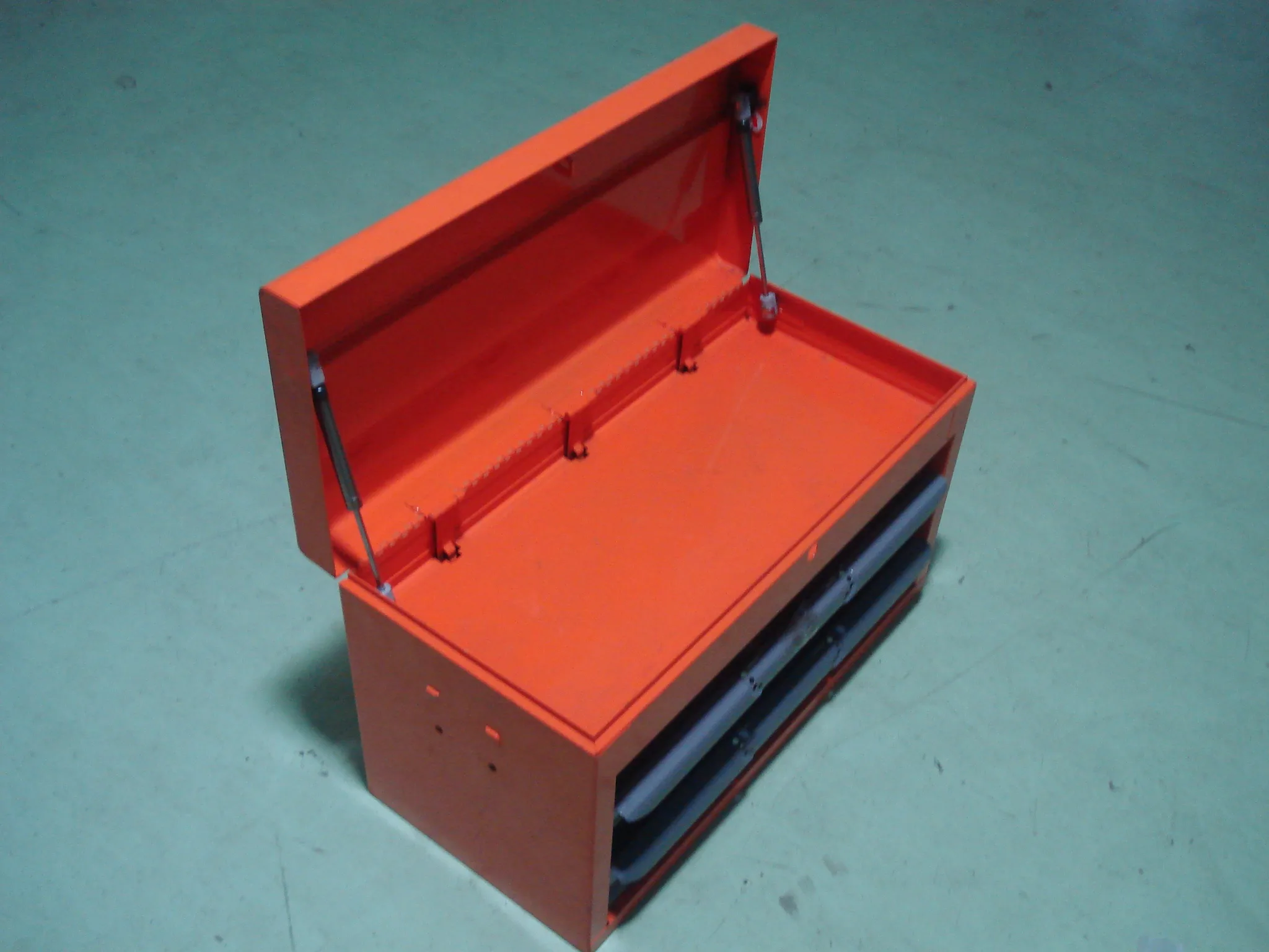 Gas springs supporting a red metal toolbox lid